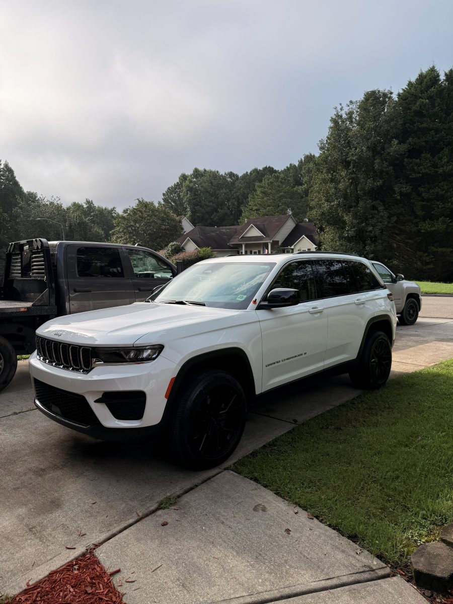 White Jeep Grand Cherokee with tinted glass and blacked-out wheels in a driveway