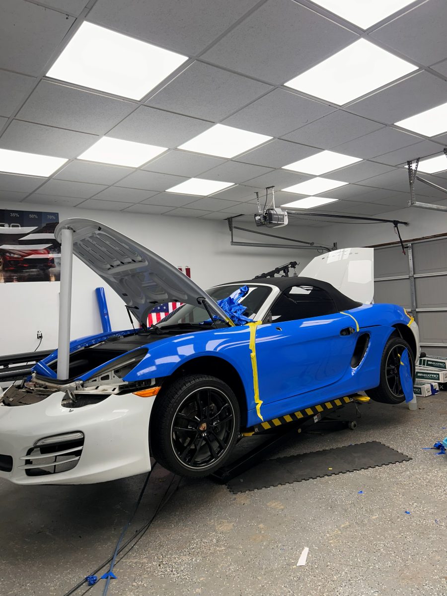 Porsche Boxster part way through a blue color change wrap, with the original white paint still showing
